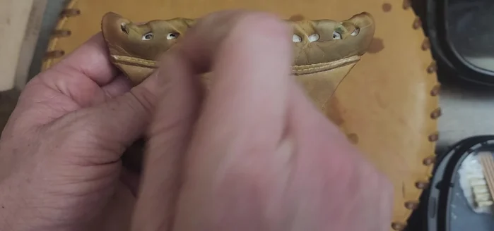 For stubborn dirt trapped in the holes of the glove, use a lacing needle to gently poke and loosen the dirt, then wipe clean.