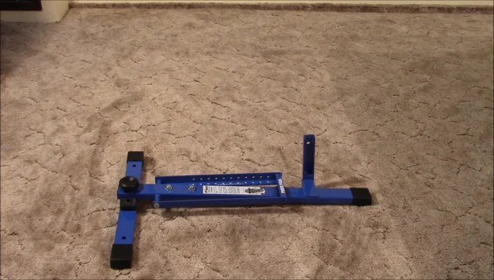 Remove the large hand screw from the base assembly and use it to attach the front leg assembly.