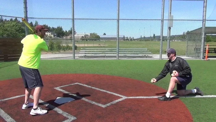Toss the ball to the batter's mid-thigh area, aligned with their front foot.