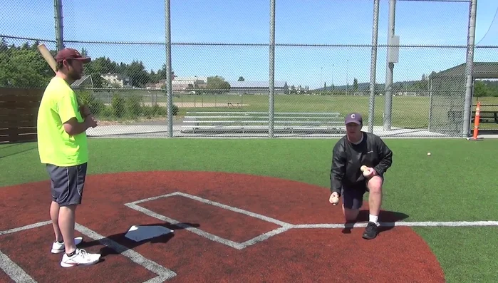 Toss the ball to the batter's mid-thigh area, aligned with their front foot.