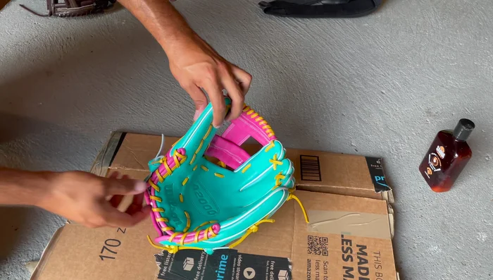 Establish Break Points: Place a baseball in the pocket. Bend the glove at the thumb hinge (near the thumb loop and Wilson logo) and pinky hinge (around the laces near the pinky).