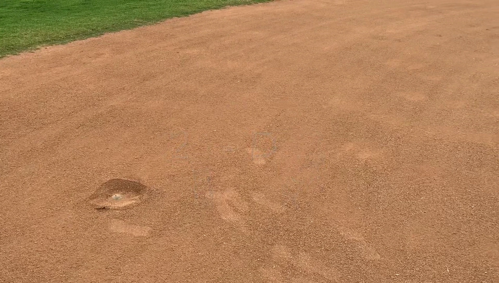 Close-up revealing loose material on the infield surface near second base.