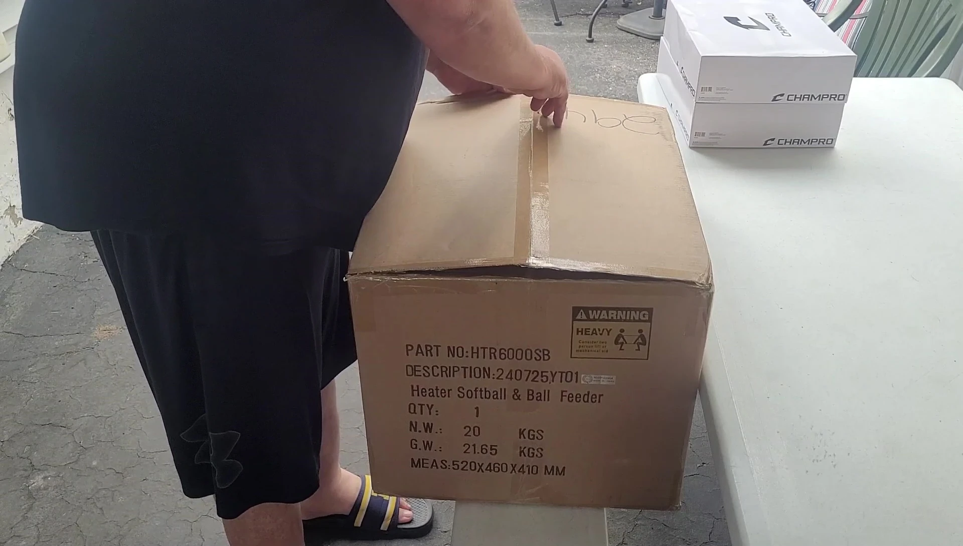 Close-up of the unboxing process, showing the pitching machine, softballs and net.