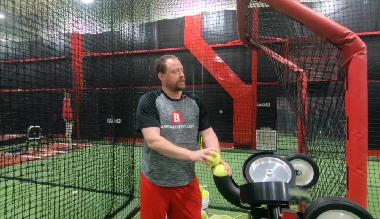 Coach demonstrating the simulated pitching motion with the Spinball machine