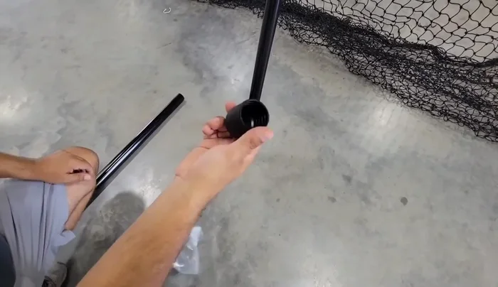 With assistance, lift the frame and attach the remaining poles to complete the 10ft height. Use bungee cords to secure the net to the crossbars for easier handling.